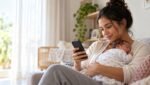 Mãe com bebê consultando pedido de salário-maternidade pelo celular